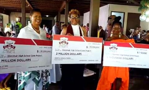 Glenmuir alumni holding presentation checks at a fundraising event