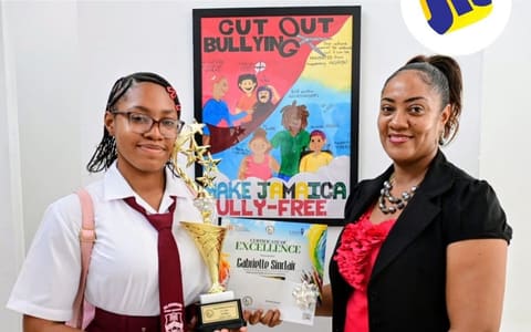 Gabrielle Sinclair in her Glenmuir uniform holding her trophy and certificate in front of her ‘Cut Out Bullying’ poster